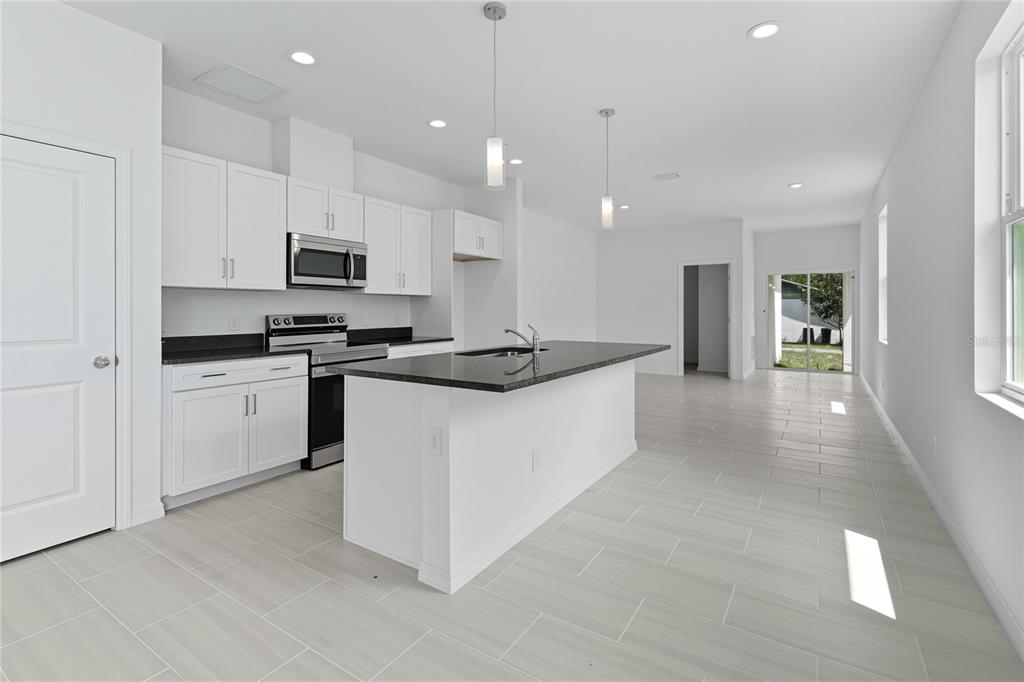 A modern kitchen features white cabinets, dark granite countertops, a center island, and tile flooring — 817 S LOCUST AVENUE, SANFORD, FL