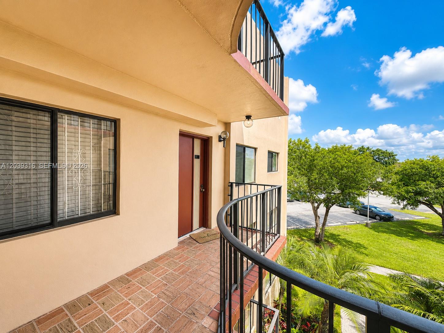 An exterior balcony features a tiled floor, a red door, and a black metal railing — 8700 SW 133rd Ave Rd # 312, Miami FL 33183, MIAMI, FL
