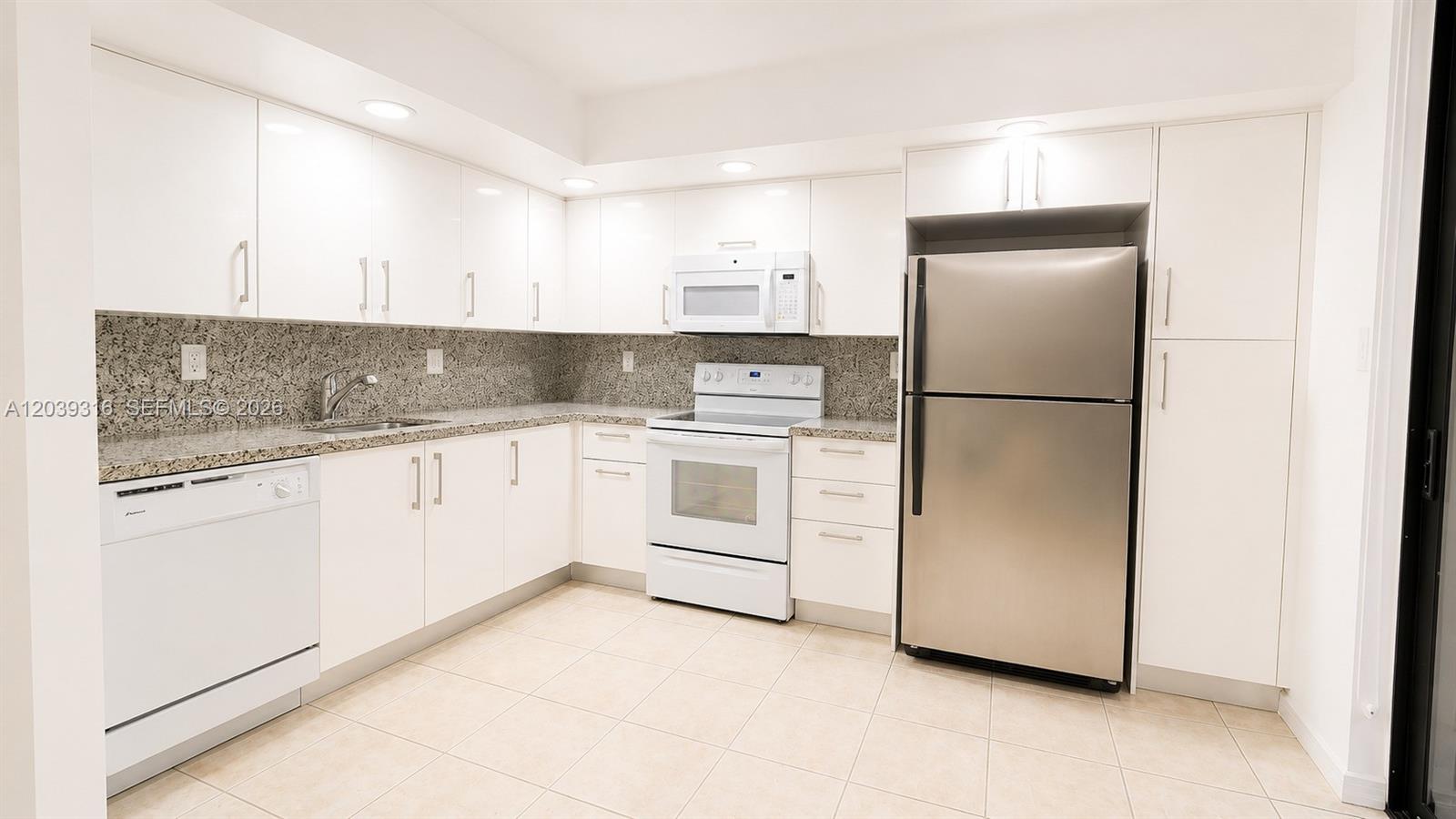 A kitchen features white cabinets, stainless steel appliances, and granite countertops — 8700 SW 133rd Ave Rd # 312, Miami FL 33183, MIAMI, FL