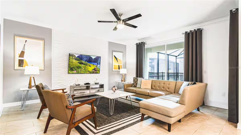 A living room features a tan sectional sofa, two armchairs, a wall-mounted television, and tile flooring — 2936 PROTAGONIST STREET, KISSIMMEE, FL
