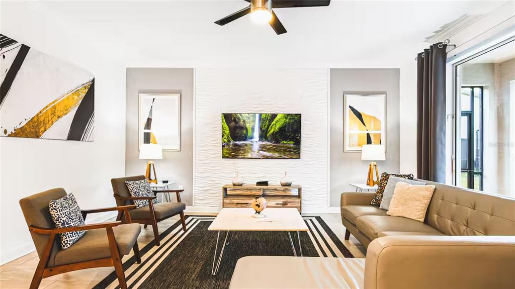 A living room features a textured white accent wall, a television, and modern furniture — 2936 PROTAGONIST STREET, KISSIMMEE, FL