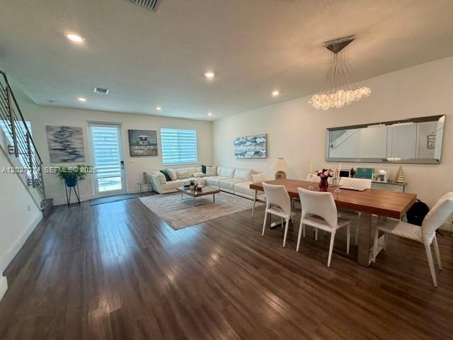 An open-concept living and dining area features wood-look flooring, recessed lighting, and a modern chandelier — DORAL, FL