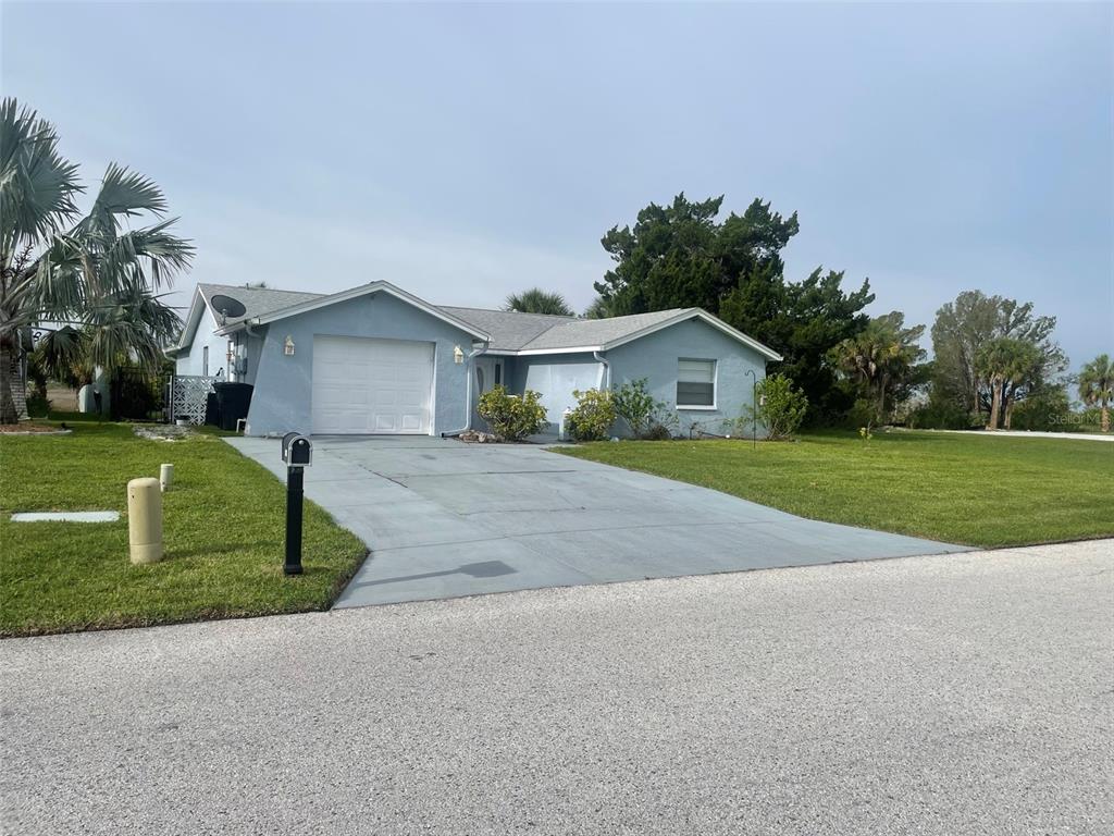 A light blue single-story house with a white garage door and a concrete driveway — 7128 SOUTHWIND DRIVE, HUDSON, FL