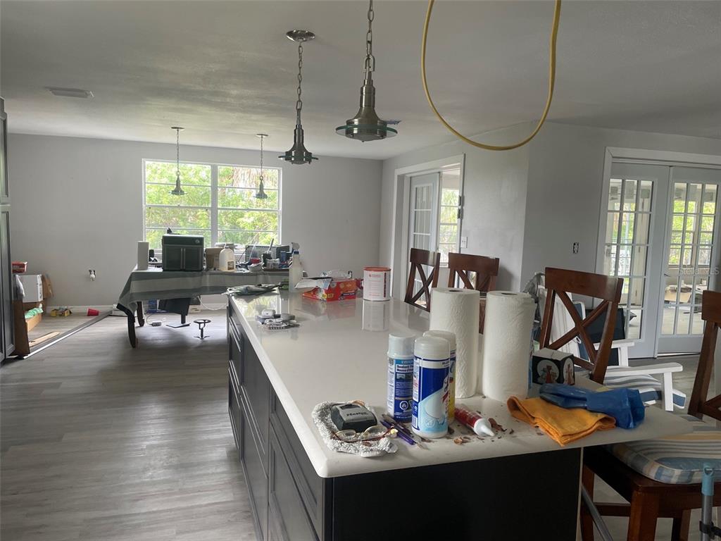 A kitchen with dark cabinets, a white island, and a dining area with a table — 7128 SOUTHWIND DRIVE, HUDSON, FL