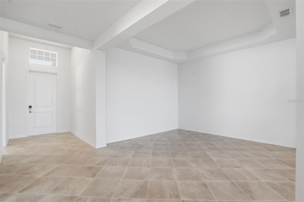 An empty room features white walls, a tray ceiling, and light-colored diagonal floor tiles — 19736 TROUT TERRACE, LAKEWOOD RANCH, FL