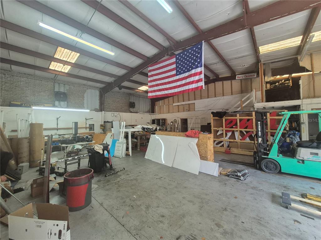 A warehouse interior features a large American flag hanging from the ceiling and a forklift — 1635 DALE MABRY HIGHWAY, LUTZ, FL