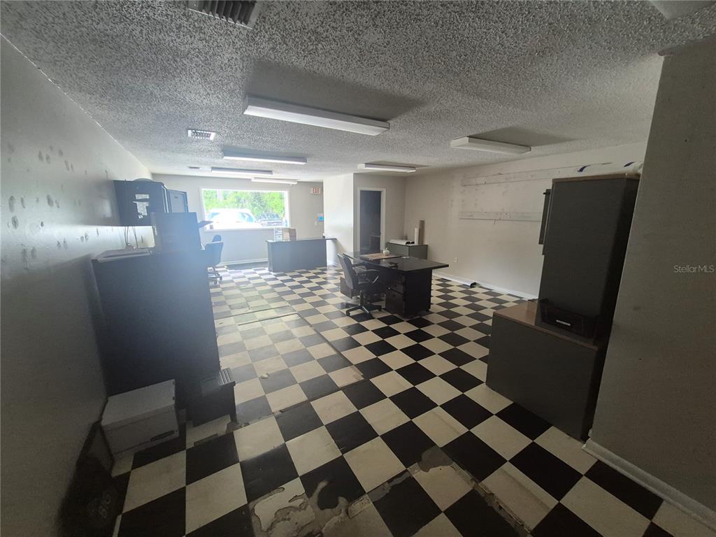 An office space features a black-and-white checkered floor, drop ceiling lights, and several desks — 1635 DALE MABRY HIGHWAY, LUTZ, FL