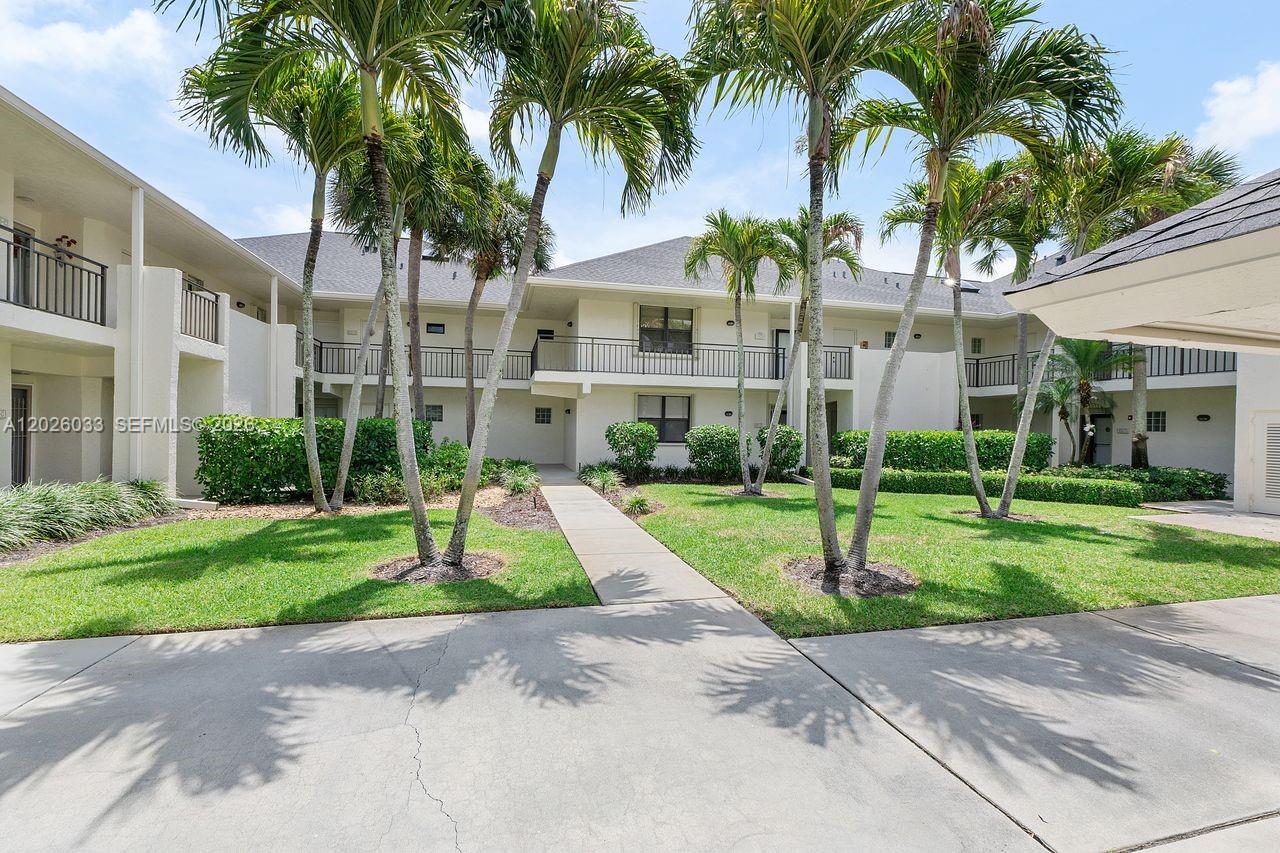 A bright living room features white sofas, a large wooden coffee table, and vaulted ceilings — 10411 SE Terrapin Place # 203, Jupiter FL 33469, JUPITER, FL