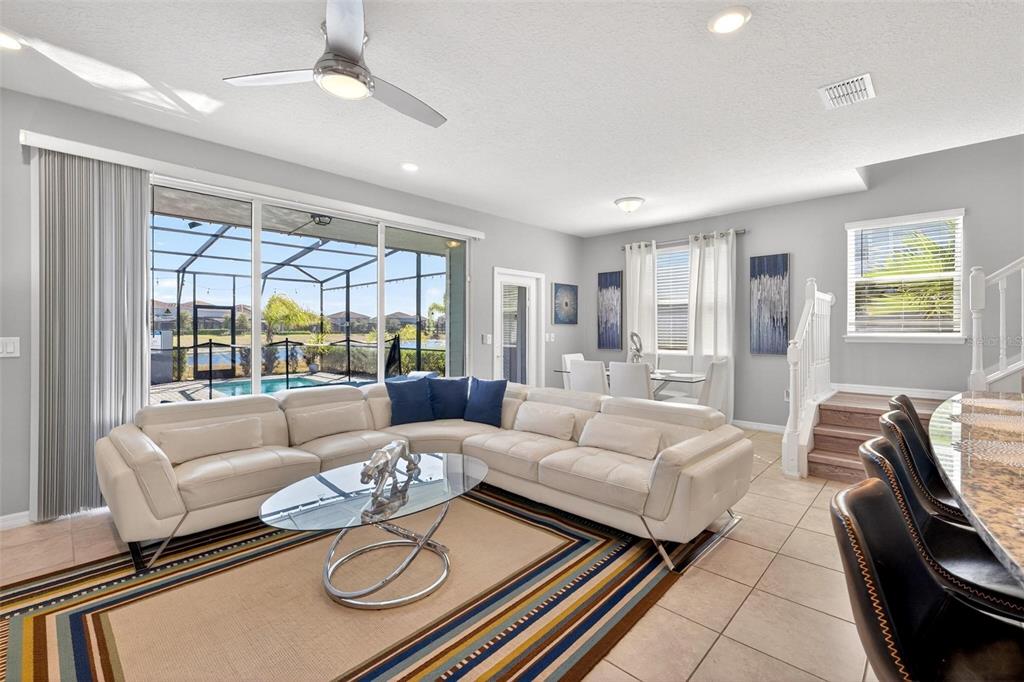 A living room features a white sectional sofa, glass coffee table, and sliding glass doors — 7554 OAK SPRING LANE, DAVENPORT, FL