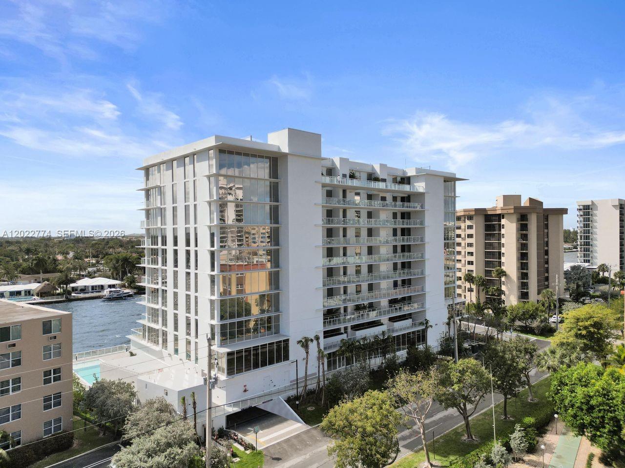 An exterior view of a modern white mid-rise apartment building next to a waterway — 407 N Riverside # 402, Pompano Beach FL 33062, POMPANO BEACH, FL