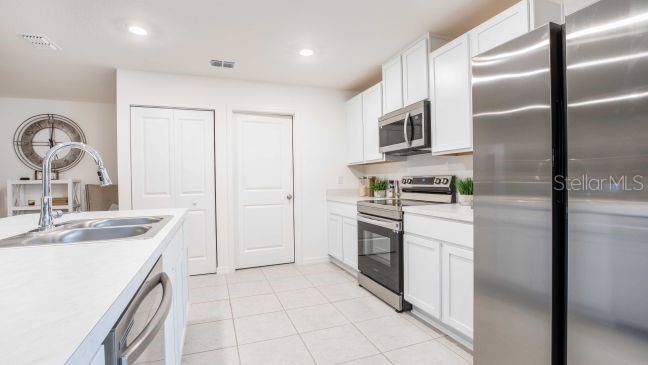 A kitchen with white cabinets, stainless steel appliances, a center island, and tile flooring — 3216 E ANDERSON STREET, INVERNESS, FL