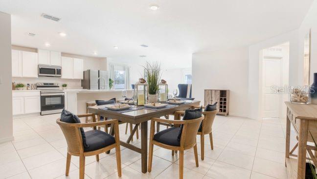 A dining area with a wooden table and chairs sits adjacent to a white kitchen — 3216 E ANDERSON STREET, INVERNESS, FL