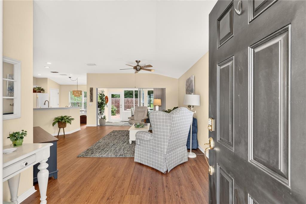 A covered front porch features a black door, a wicker chair, and decorative wall accents — 13088 SE 86TH CIRCLE, SUMMERFIELD, FL