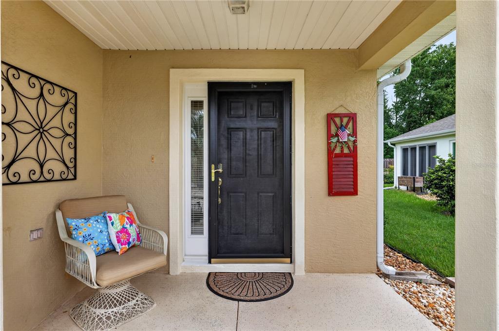 An open-concept living room with wood-look flooring is viewed from an open front door — 13088 SE 86TH CIRCLE, SUMMERFIELD, FL