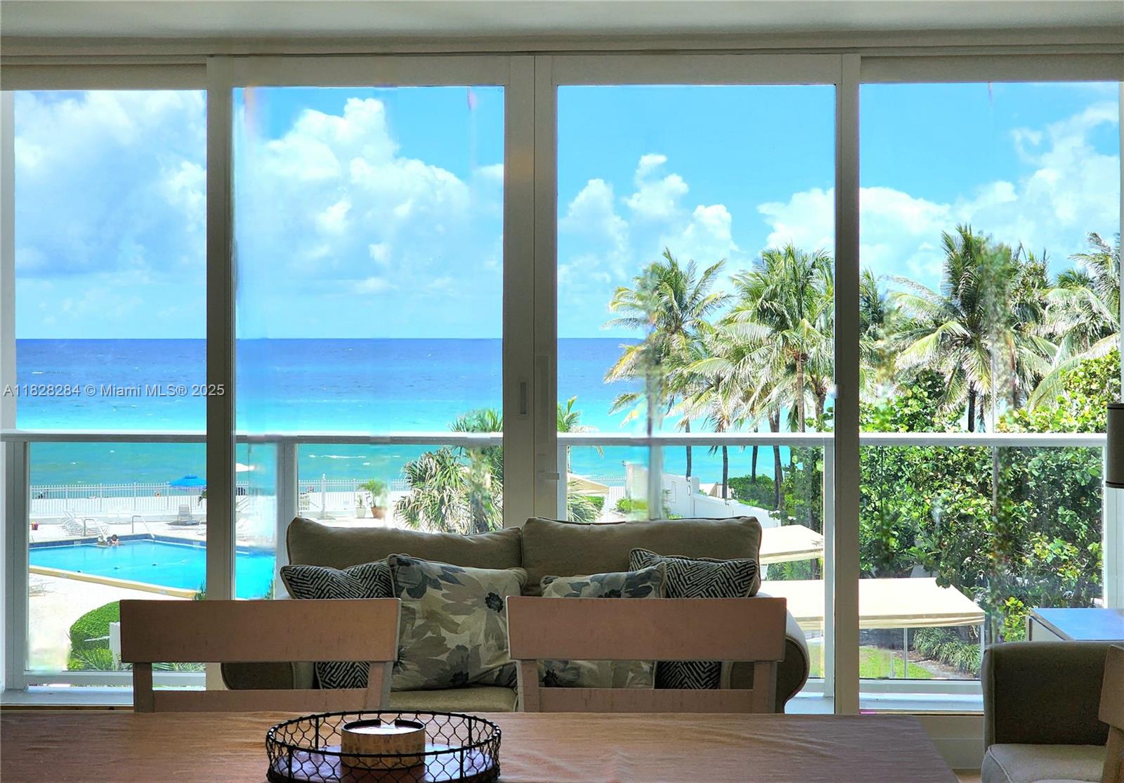 A dining area overlooks a balcony, swimming pool, and the ocean through large glass doors — 3505 S Ocean Dr # 320, Hollywood FL 33019, HOLLYWOOD, FL