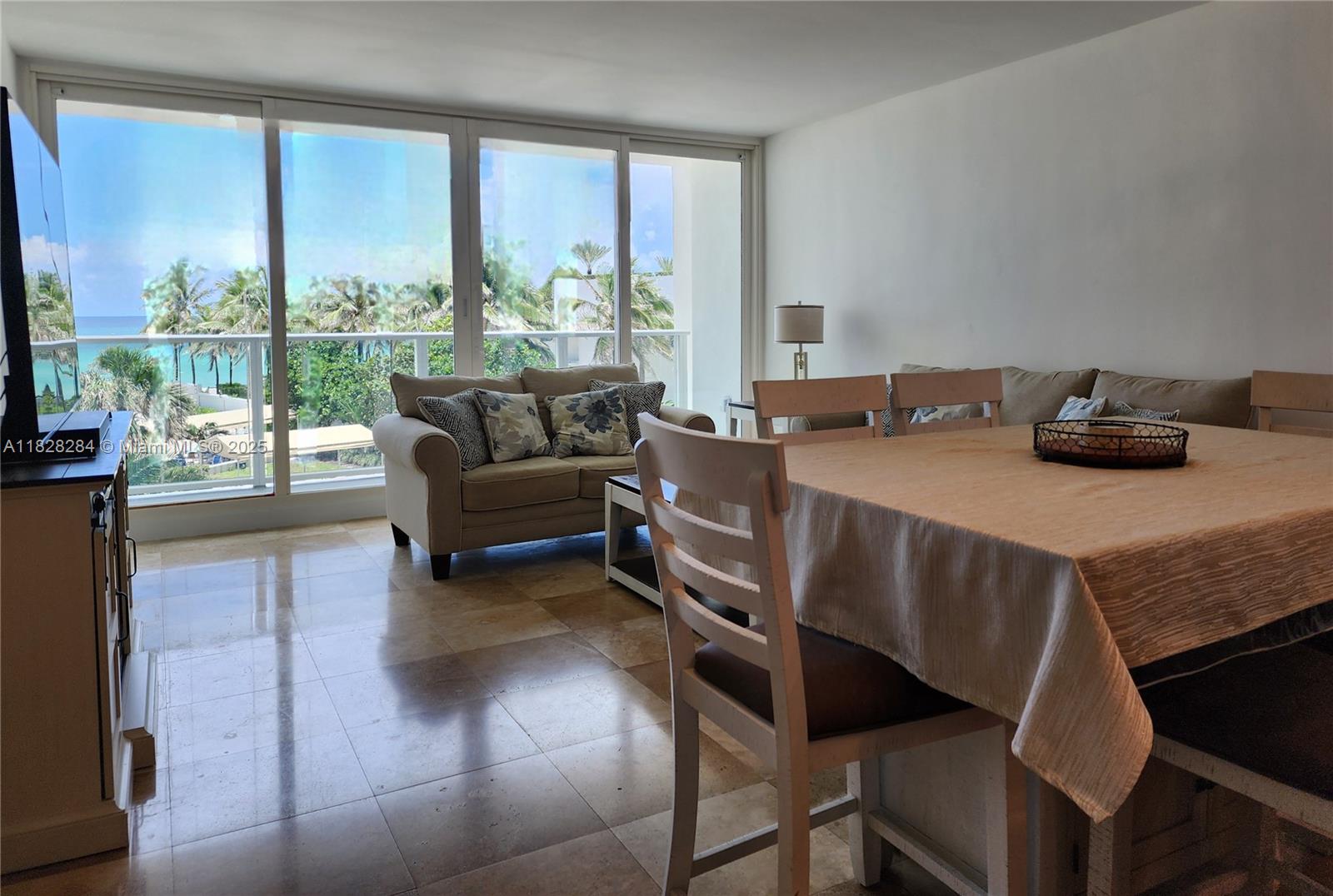 A dining area and living room with tile floors overlook a balcony and ocean view — 3505 S Ocean Dr # 320, Hollywood FL 33019, HOLLYWOOD, FL