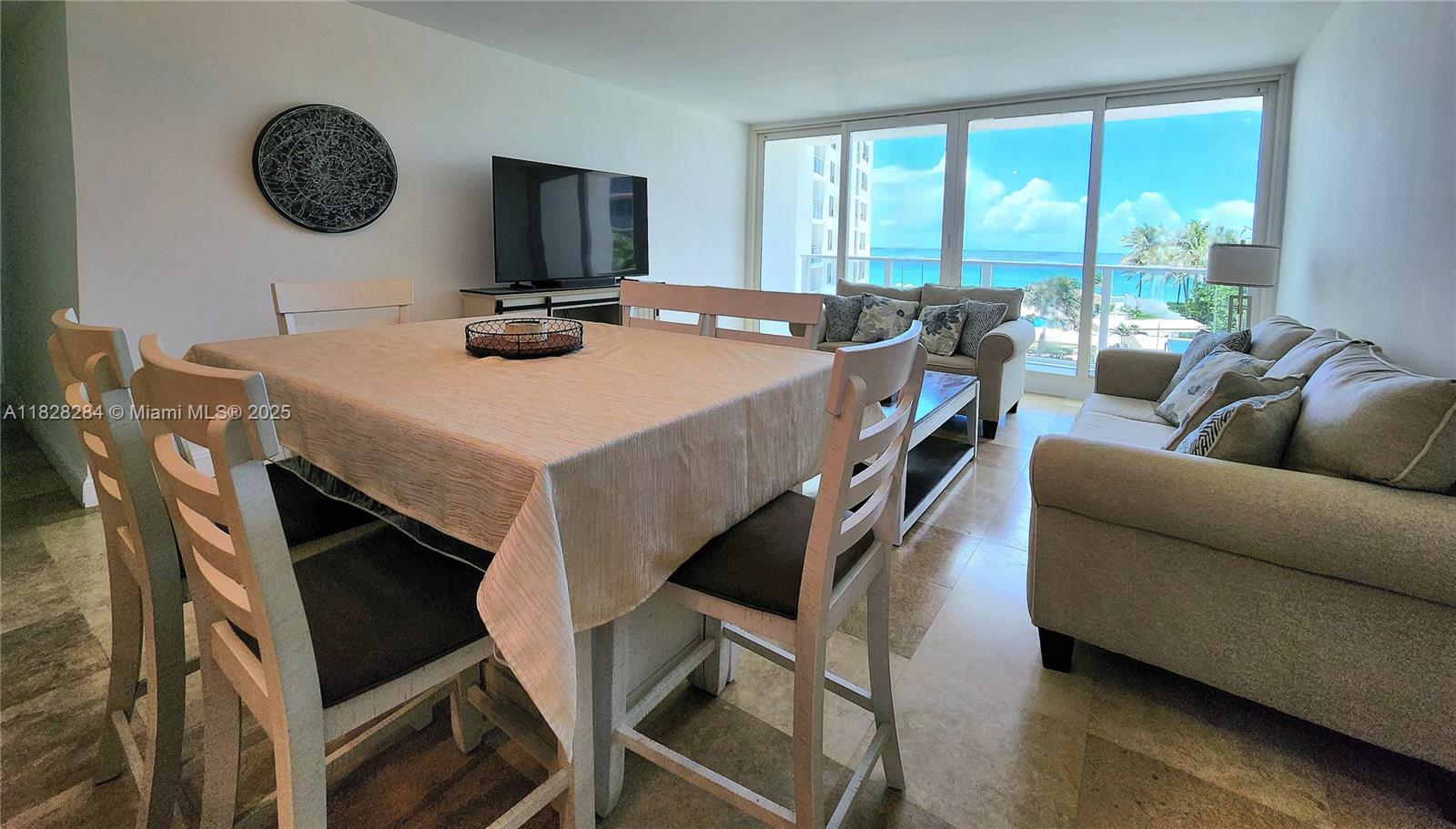 A living and dining area features tile floors, a table, and a balcony with ocean views — 3505 S Ocean Dr # 320, Hollywood FL 33019, HOLLYWOOD, FL