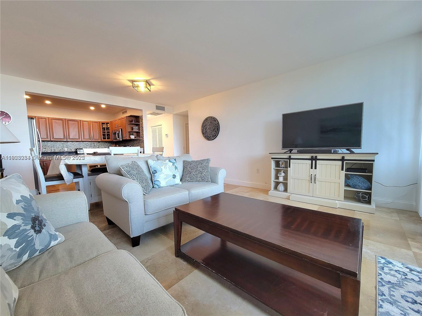 A living room features a light-colored sofa, a dark wood coffee table, and a television console — 3505 S Ocean Dr # 320, Hollywood FL 33019, HOLLYWOOD, FL