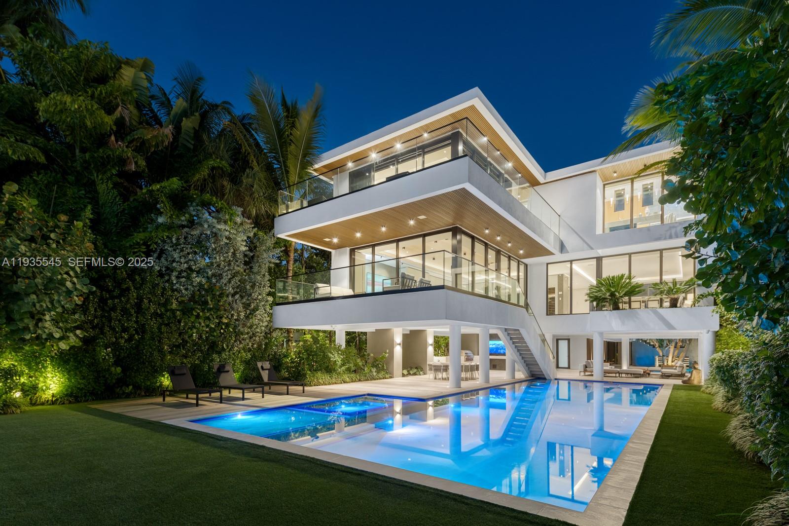 A modern multi-story house with a swimming pool, glass balconies, and outdoor lounge areas at night — 40 W Rivo Alto Dr, Miami Beach FL 33139, MIAMI BEACH, FL