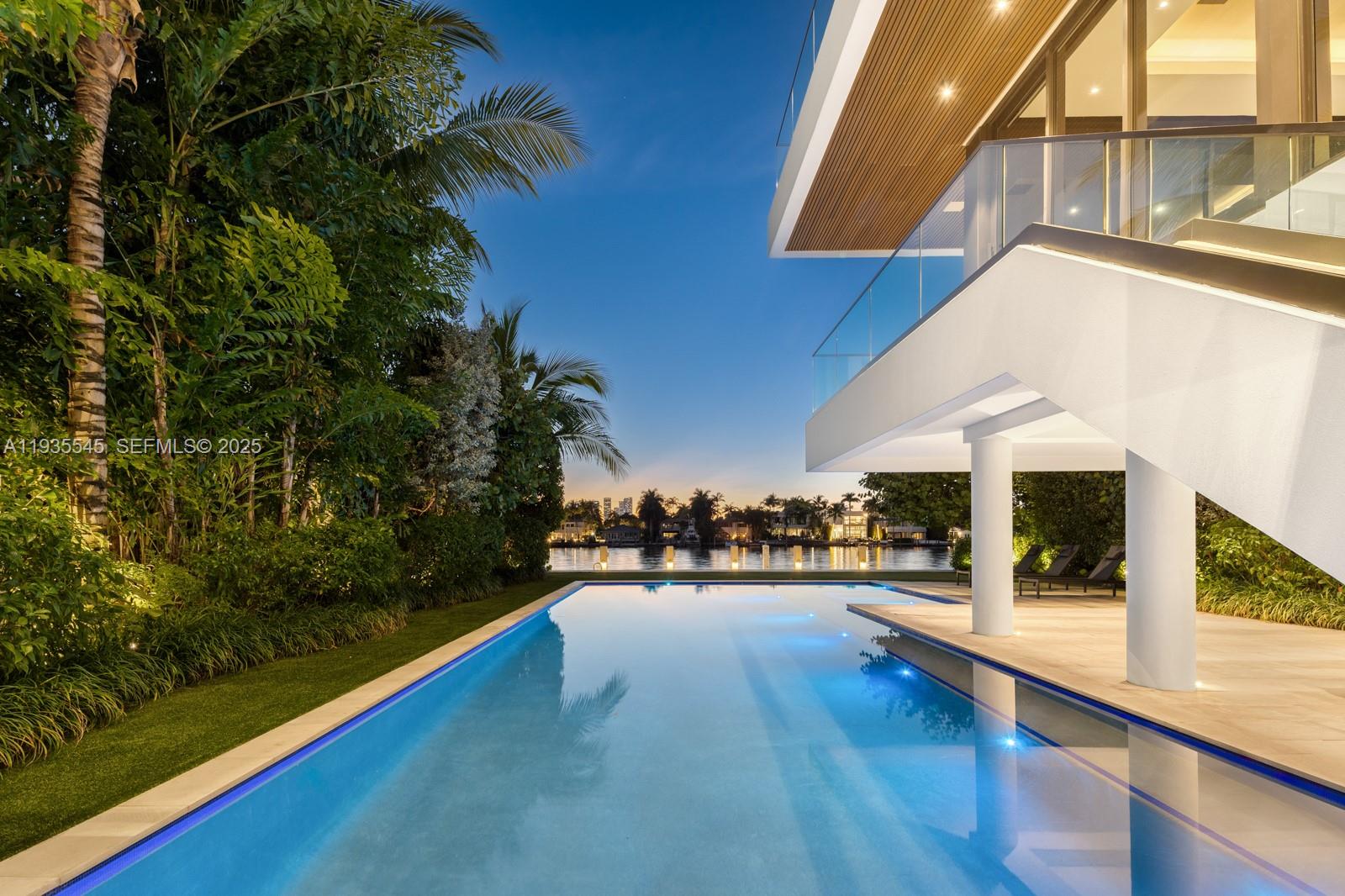 A modern house with a swimming pool overlooks a waterfront view at twilight — 40 W Rivo Alto Dr, Miami Beach FL 33139, MIAMI BEACH, FL