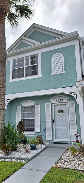 A two-story teal townhouse with white trim, a front door, and a small landscaped yard — 5052 MISTY CANAL PL, BRADENTON, FL