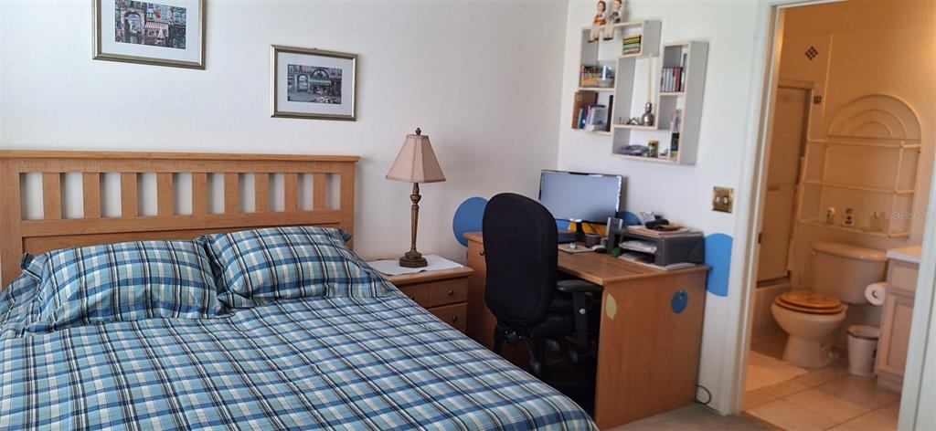 A bedroom features a plaid-covered bed, a wooden desk with a computer, and an attached bathroom — 5052 MISTY CANAL PL, BRADENTON, FL