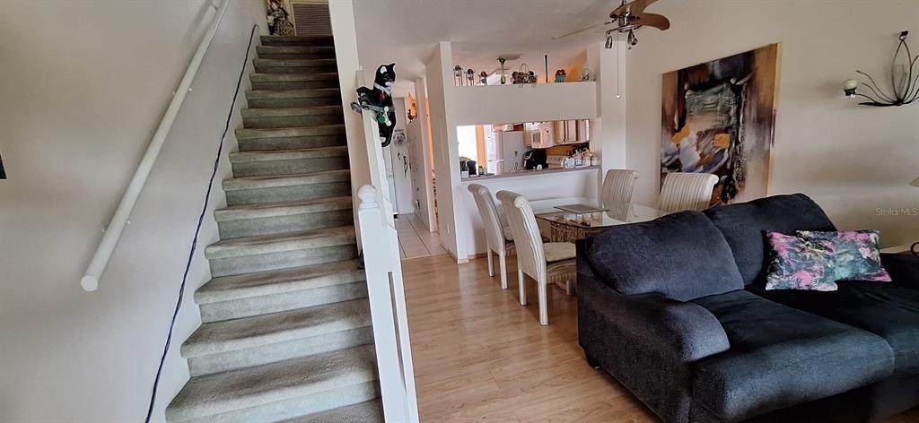 A carpeted staircase leads upstairs next to a living area with a dark sofa — 5052 MISTY CANAL PL, BRADENTON, FL