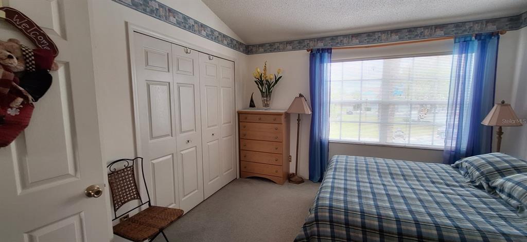 A bedroom features a plaid bedspread, a wooden dresser, a closet, and blue curtains — 5052 MISTY CANAL PL, BRADENTON, FL