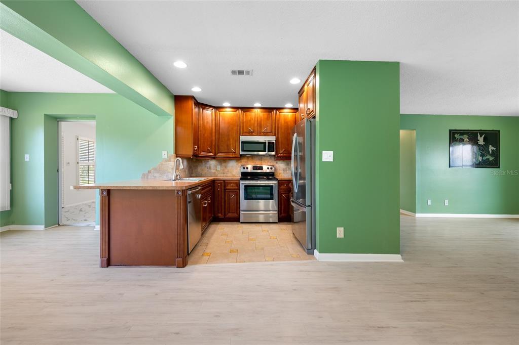 A kitchen with wood cabinets, stainless steel appliances, and green walls — 8440 BRENTWOOD ROAD, SEMINOLE, FL