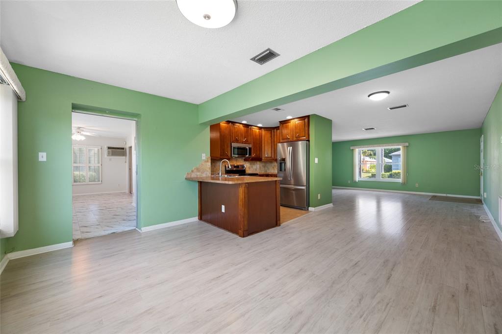 An open-concept living area features light wood flooring, green walls, and a kitchen with wood cabinets — 8440 BRENTWOOD ROAD, SEMINOLE, FL
