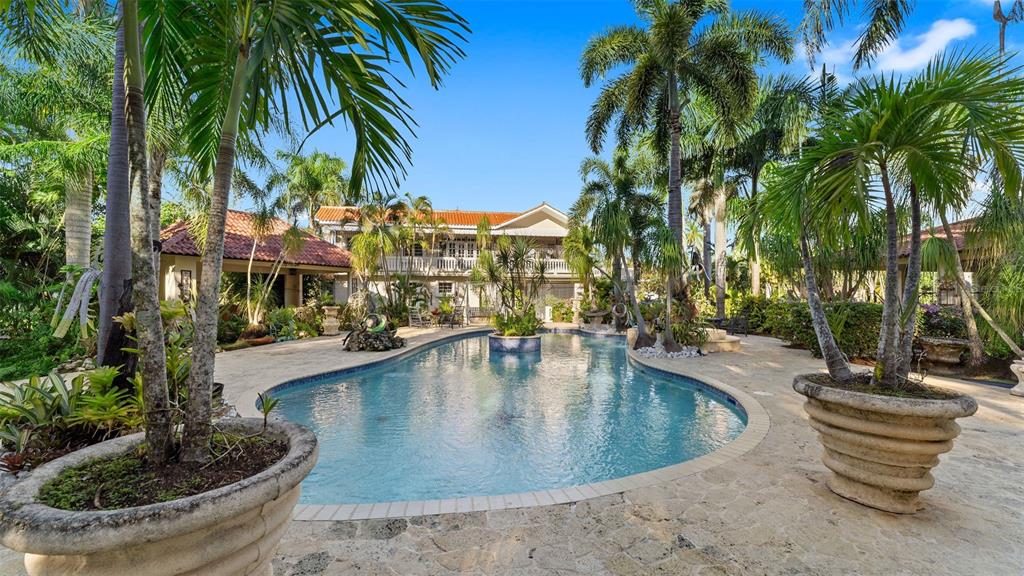 A swimming pool sits in a stone patio surrounded by palm trees and a two-story house — Carr. 311 km 0.3 BO. BAJURA, CABO ROJO, PR