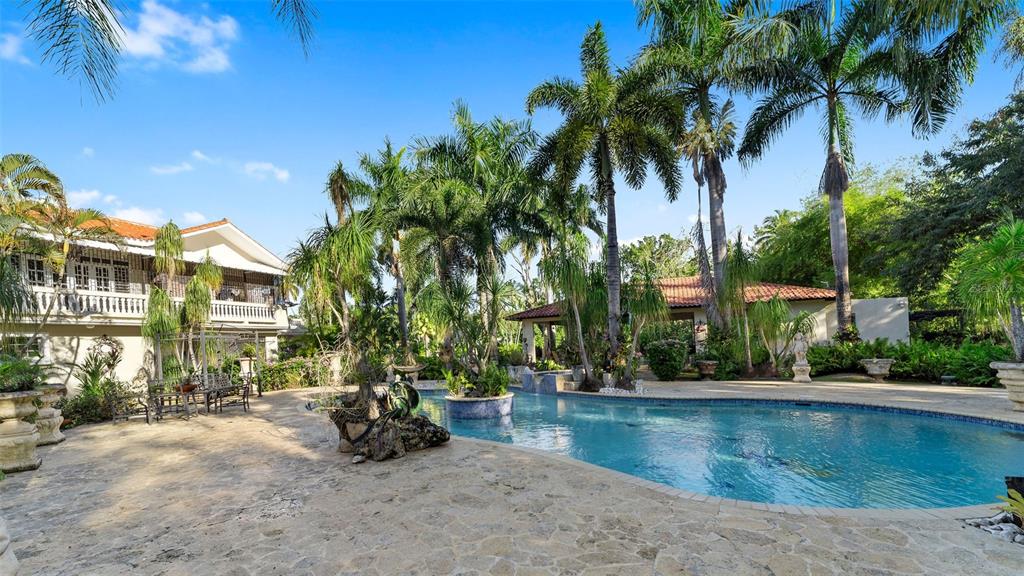 A swimming pool sits in a stone-paved courtyard surrounded by palm trees and two buildings — Carr. 311 km 0.3 BO. BAJURA, CABO ROJO, PR