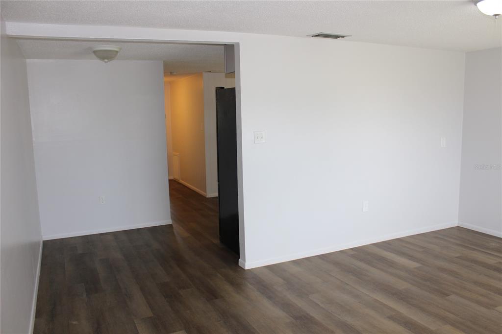 An interior view showing a living area with wood-look flooring and a black refrigerator — 322 ORGAN STREET UNIT A & B, PUNTA GORDA, FL