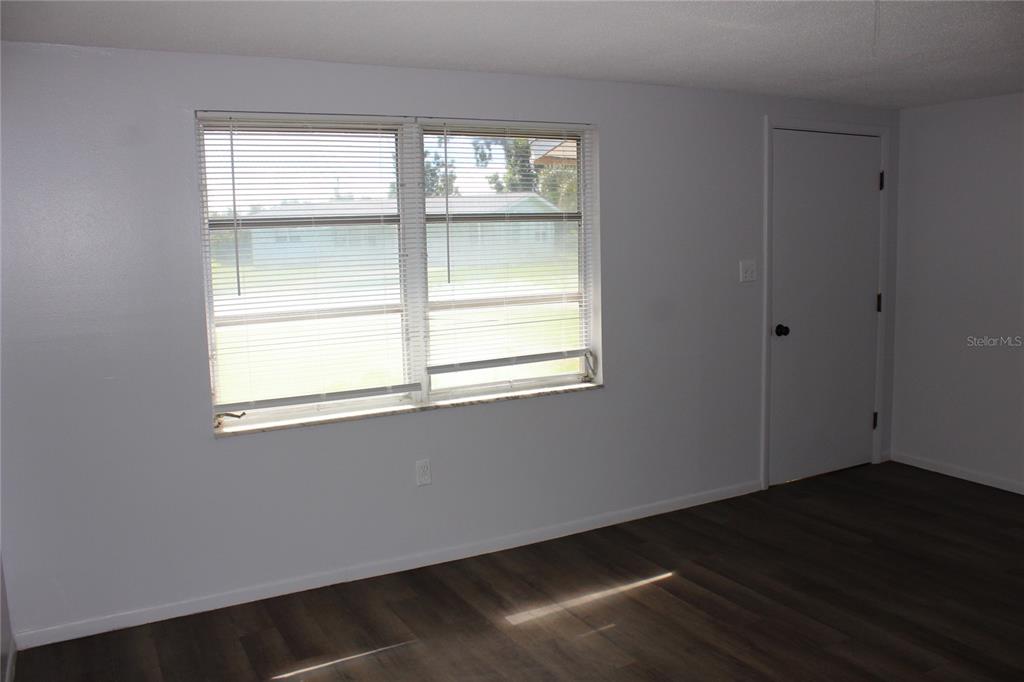 A room with light gray walls, dark wood-look flooring, a window with blinds, and a door — 322 ORGAN STREET UNIT A & B, PUNTA GORDA, FL
