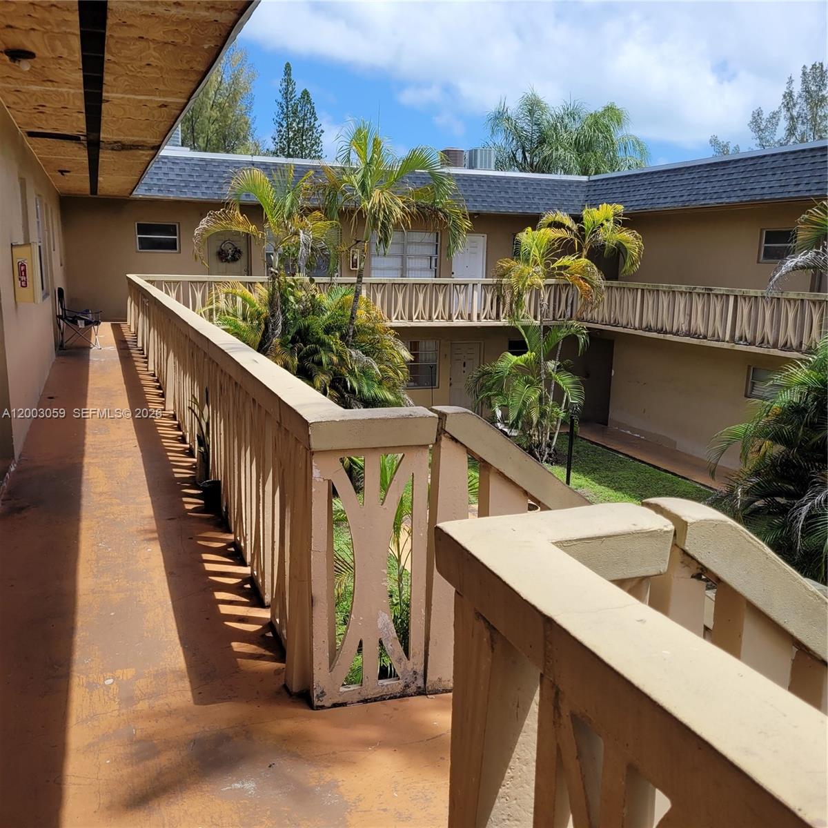 An outdoor walkway overlooks a courtyard with palm trees at a multi-story apartment complex — 1370 NE 119th St # 137015, Miami FL 33161, MIAMI, FL