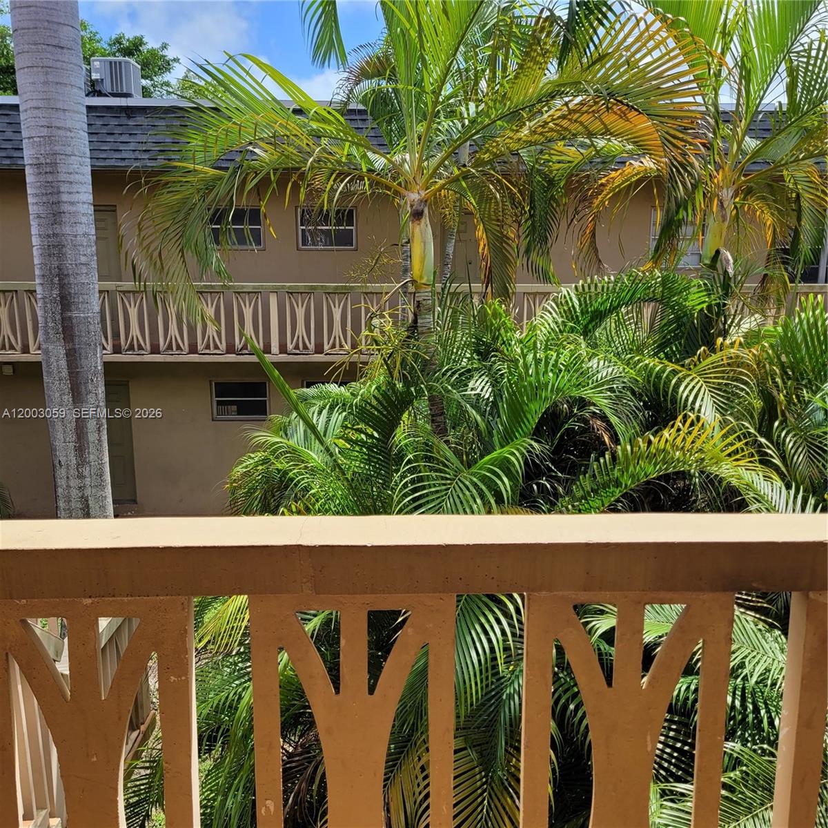 A view from a balcony looking toward a neighboring building and lush palm trees — 1370 NE 119th St # 137015, Miami FL 33161, MIAMI, FL