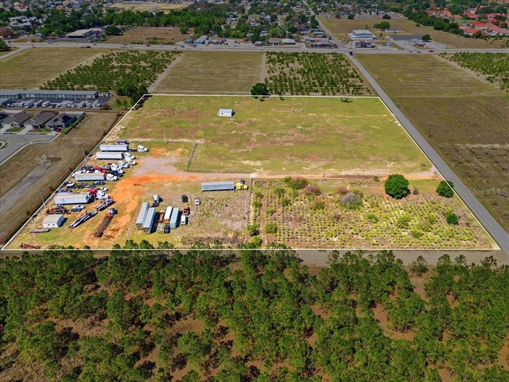 An aerial view shows a large, rectangular plot of land with parked trucks and vegetation — 186 LEWIS GRIFFIN ROAD, LAKE WALES, FL