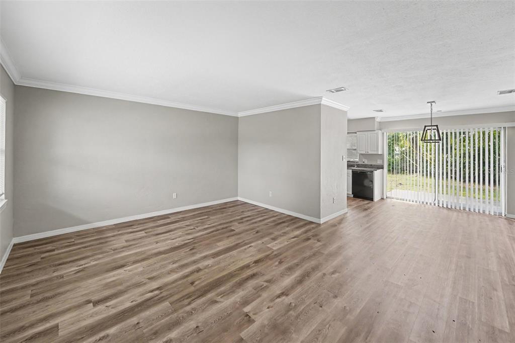 An empty living room with light gray walls, wood-look flooring, and a sliding glass door — 4101 BLUEFISH DRIVE SE, ST PETERSBURG, FL
