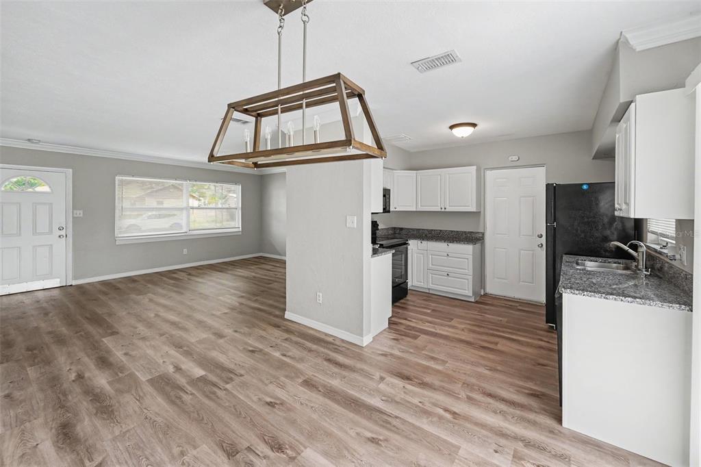 An open-concept kitchen and dining area features white cabinets, granite countertops, and wood-look flooring — 4101 BLUEFISH DRIVE SE, ST PETERSBURG, FL