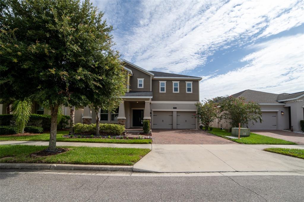 A two-story house with a brick driveway, two-car garage, and a large tree in front — 11109 SWEETGUM WOODS DRIVE, ORLANDO, FL
