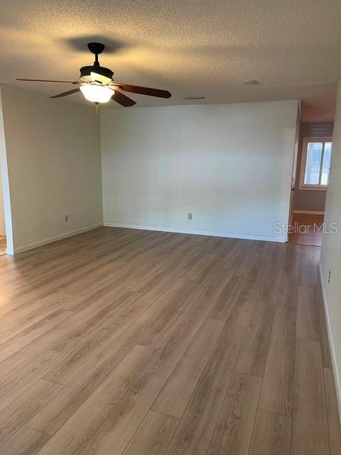 An empty room features light wood-look flooring, white walls, and a ceiling fan — 8540 SW 91ST PLACE UNIT C, OCALA, FL