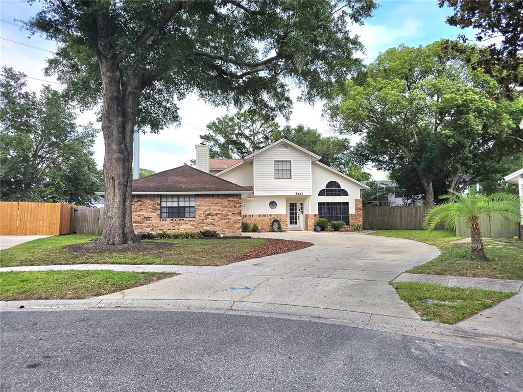 A two-story house with a brick and siding exterior, a large tree, and a concrete driveway — 8433 COMMANDER COVE, WINTER PARK, FL