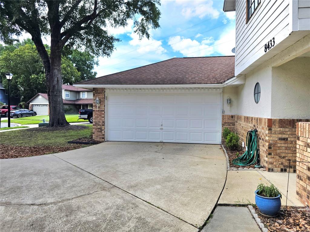 A concrete driveway leads to a white two-car garage door on a house exterior — 8433 COMMANDER COVE, WINTER PARK, FL