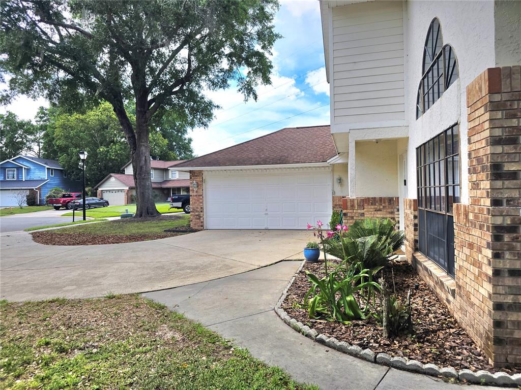 A residential exterior view showing a driveway, a two-car garage, and a brick-accented house facade — 8433 COMMANDER COVE, WINTER PARK, FL