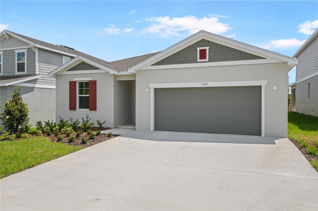 A single-story house features a gray garage, red shutters, and a green shingled gable — 1767 CARNELIAN STREET, DELAND, FL