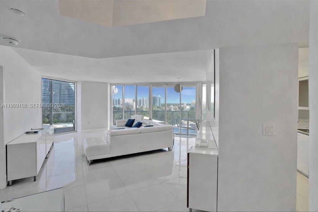 A bright living room features white tile floors, a white sectional sofa, and floor-to-ceiling windows — 7330 Ocean Ter # C, Miami Beach FL 33141, MIAMI BEACH, FL