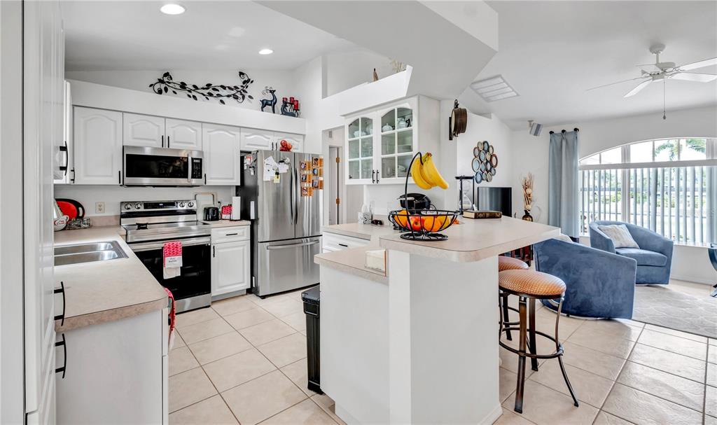 A kitchen with white cabinets and stainless steel appliances opens to a living area — 7360 N FICUS TREE, PUNTA GORDA, FL