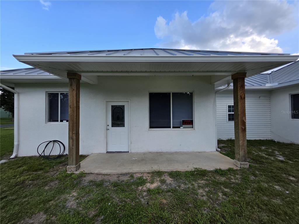 A white stucco house exterior features a covered concrete porch with two wooden support posts — 837 LILY STREET, SEBRING, FL