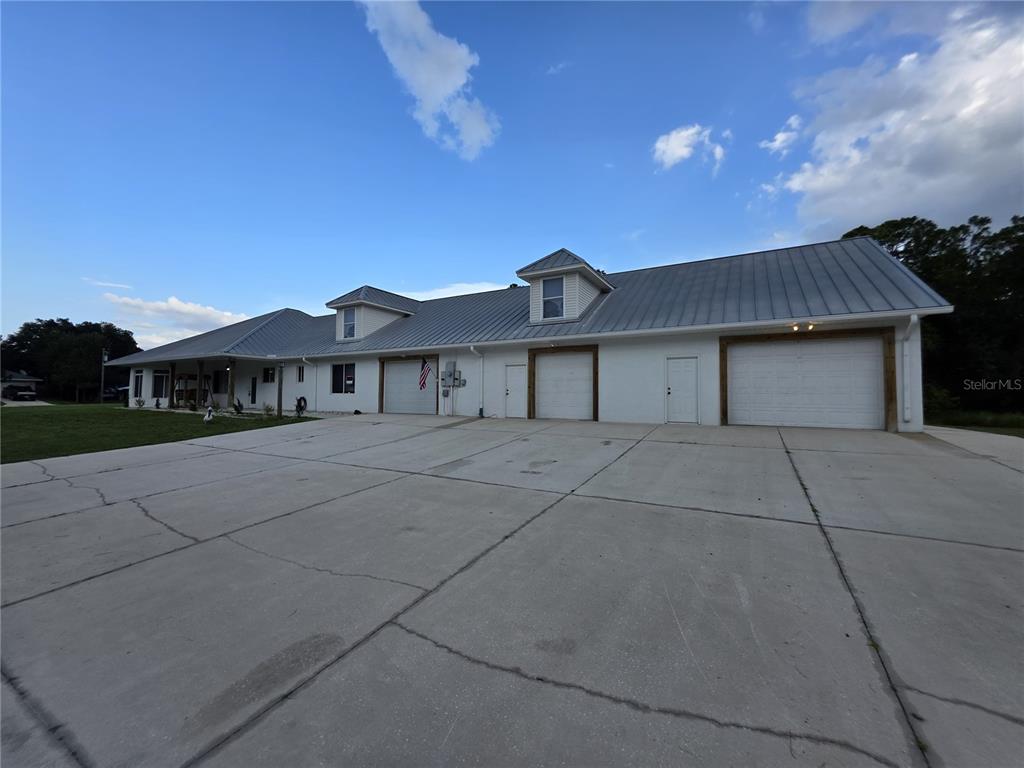 A long, white, single-story building with a metal roof and multiple garage doors — 837 LILY STREET, SEBRING, FL