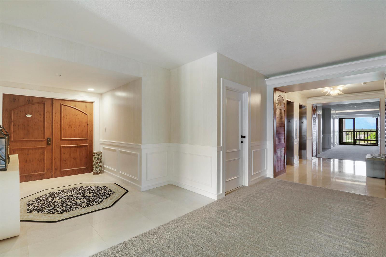 A hotel-style hallway features a wooden double door, a white door, and an elevator bank — 3322 Casseekey Island Road # 604, Jupiter FL 33477, JUPITER, FL